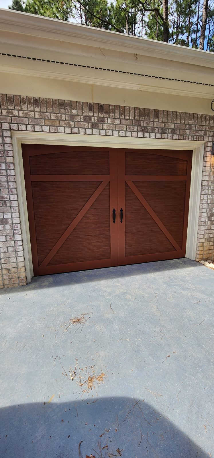 Dark garage door installation framed by brick by Premier Access Solutions